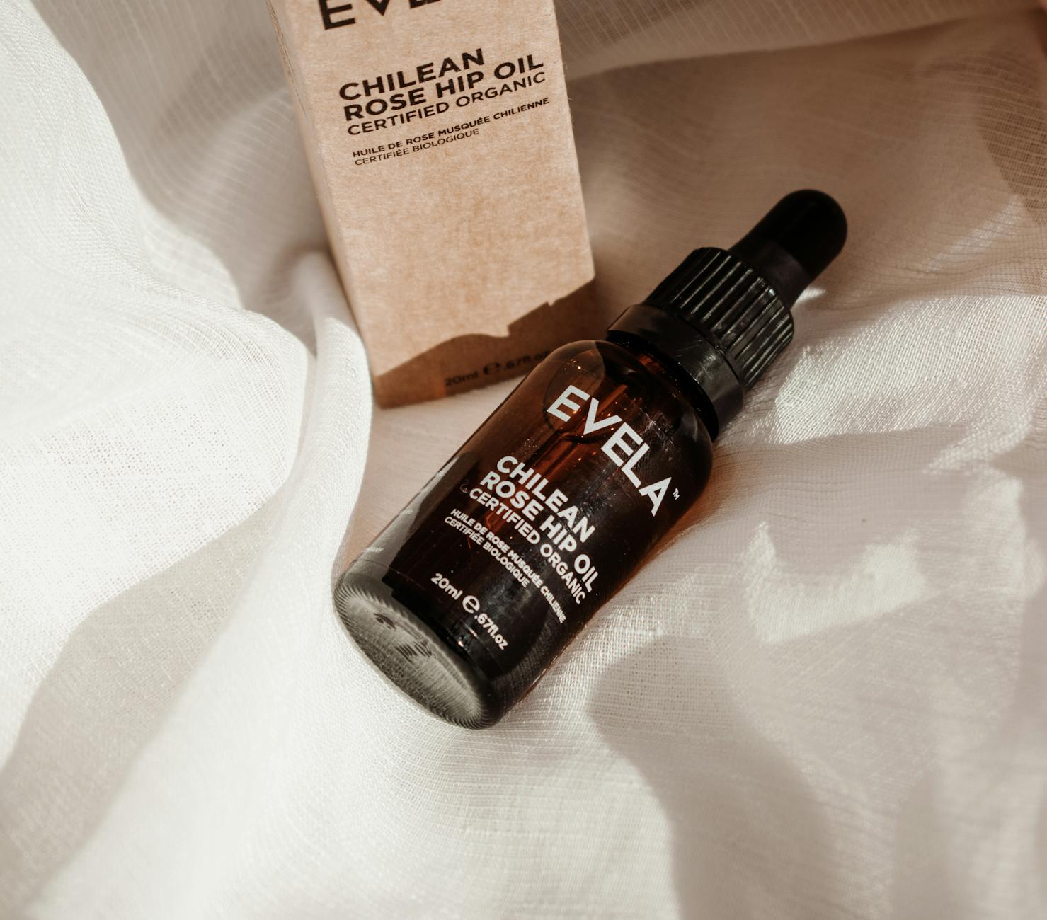 Dzianina z certyfikatem OEKO TEX: co obejmuje, a co zostaje poza kontrolą Butelka olejku różanego na białej dzianinie w naturalnym świetle